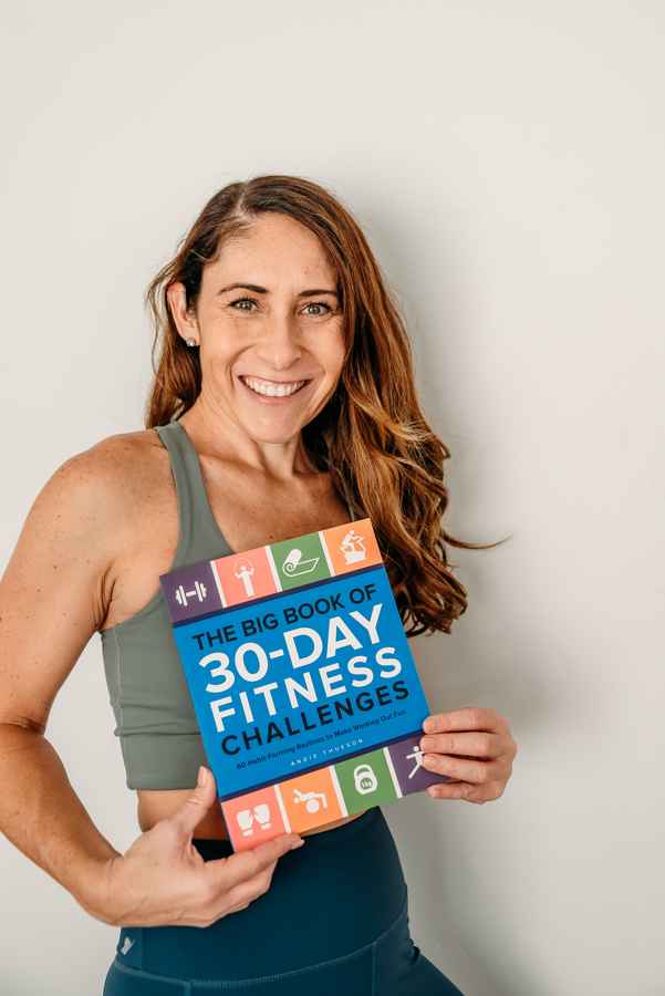 Andie holding a copy of her book The Bog Book of 30 Day Fitness Challenges 